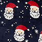 Pattern of white Santa faces in red hats with white snowflakes on a dark background