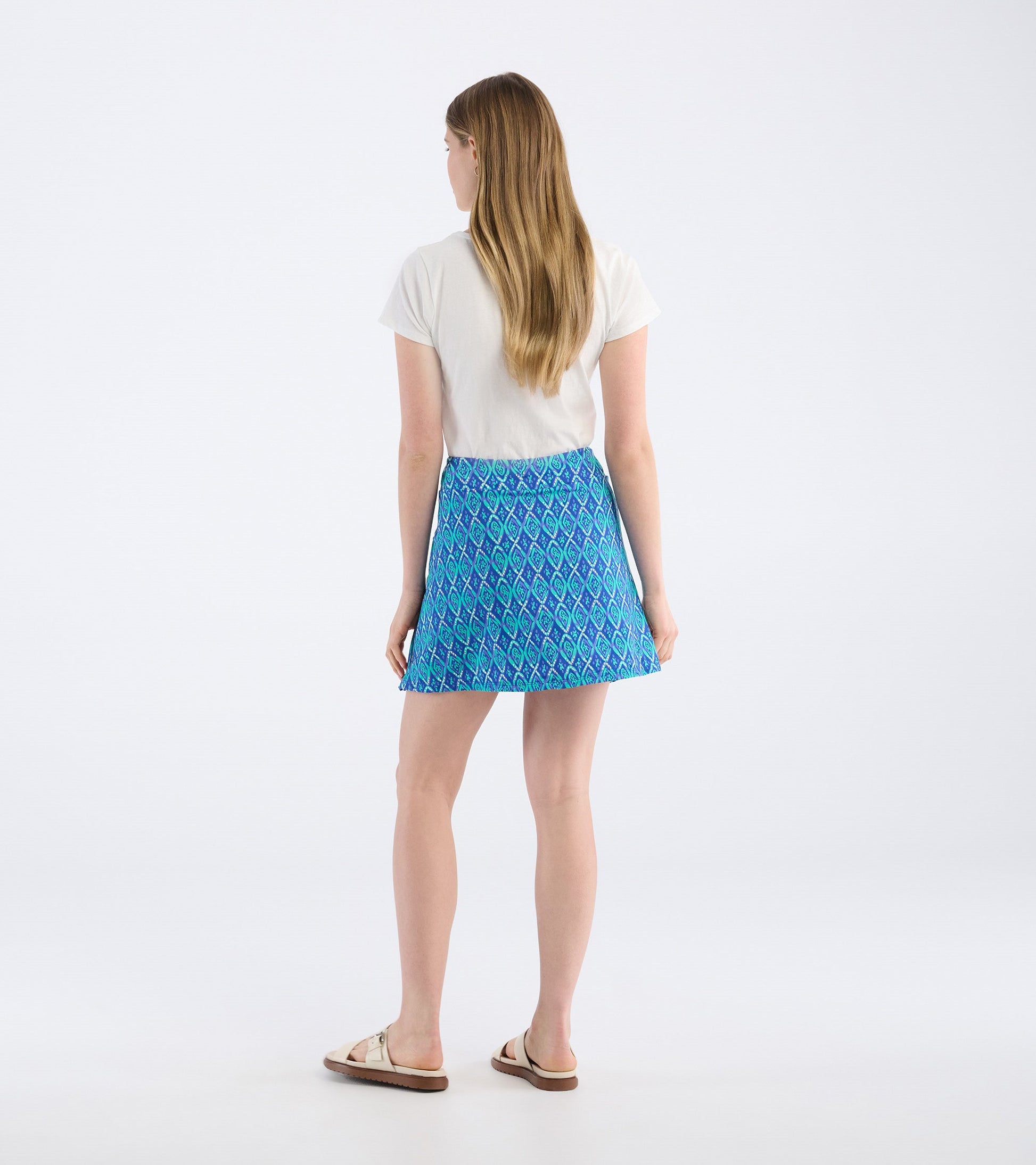 Blue skort featuring a diamond pattern, shown from the back, paired with a light top and sandals.