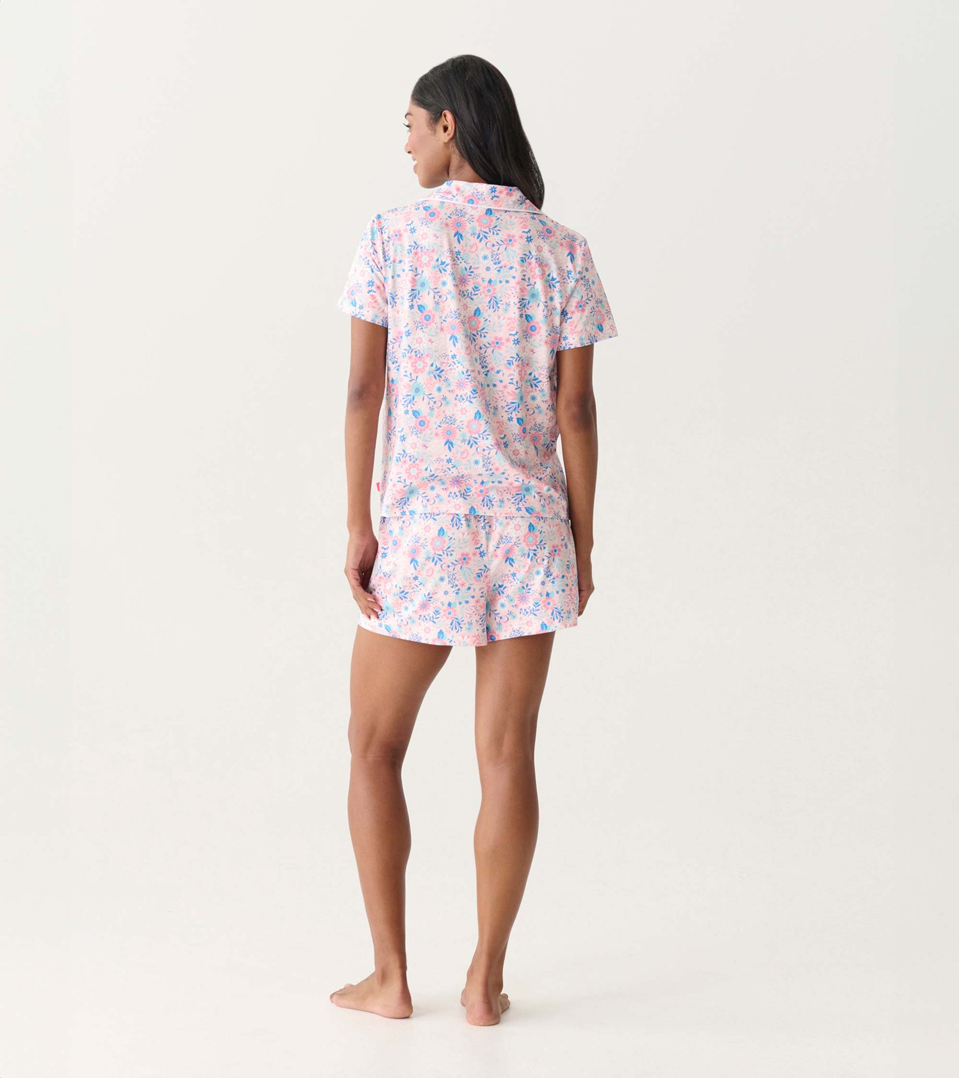 Back view of a pink and blue floral short-sleeve button-down pajama set with shorts