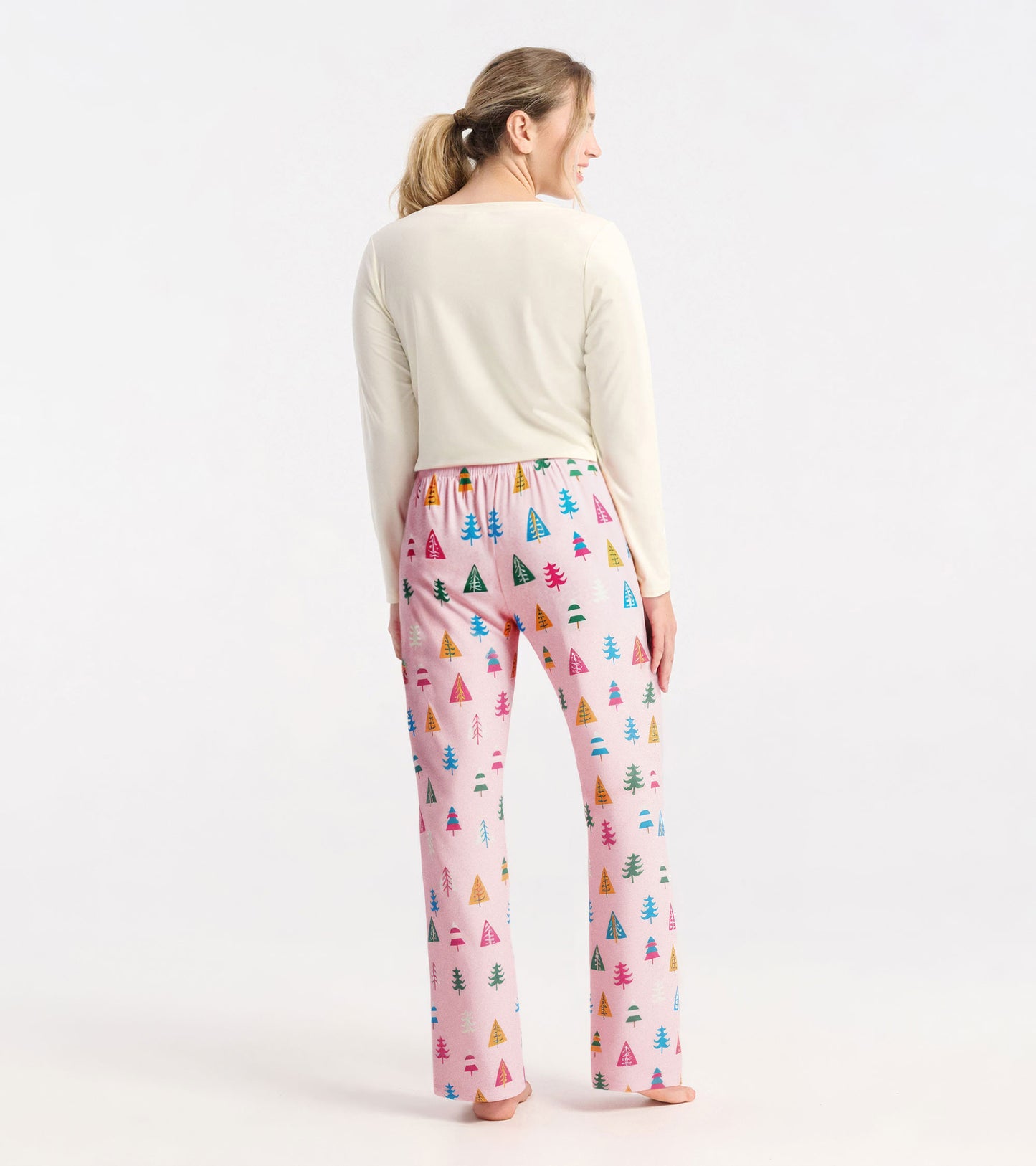 Pink polyknit pajama pants featuring colorful holiday tree patterns, with an elastic waistband and a relaxed fit.