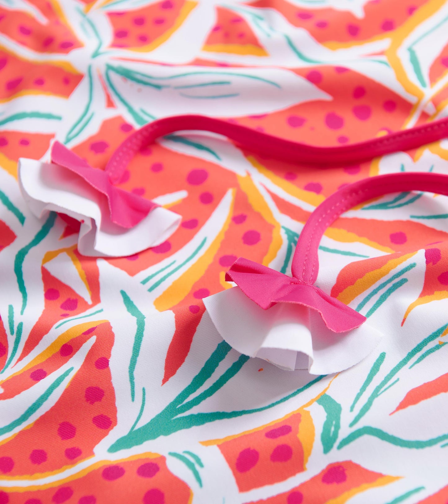 Colorful floral pattern with pink and white ruffled straps, perfect for beachwear.
