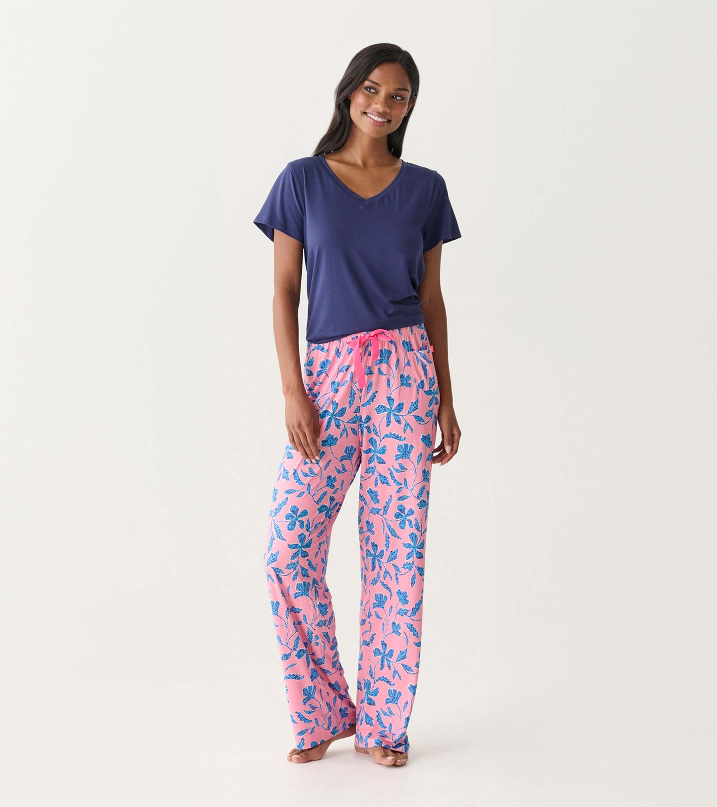 Woman wearing a navy V-neck short-sleeve T-shirt with pink floral pajama pants, front view.