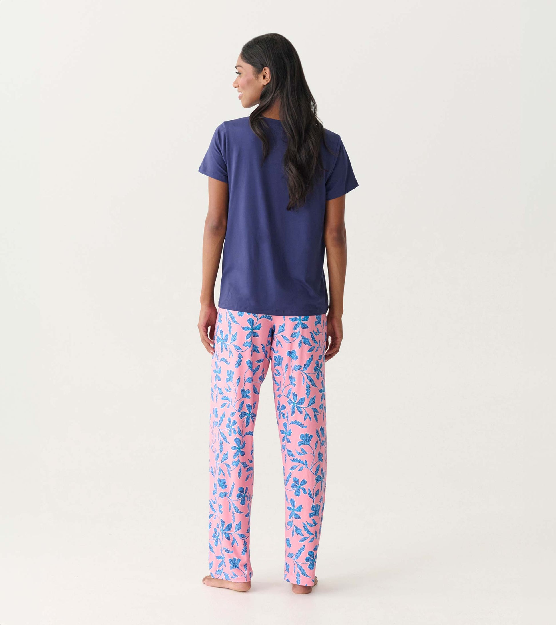 Back view of a navy V-neck short-sleeve T-shirt on a model, paired with pink floral pajama pants.