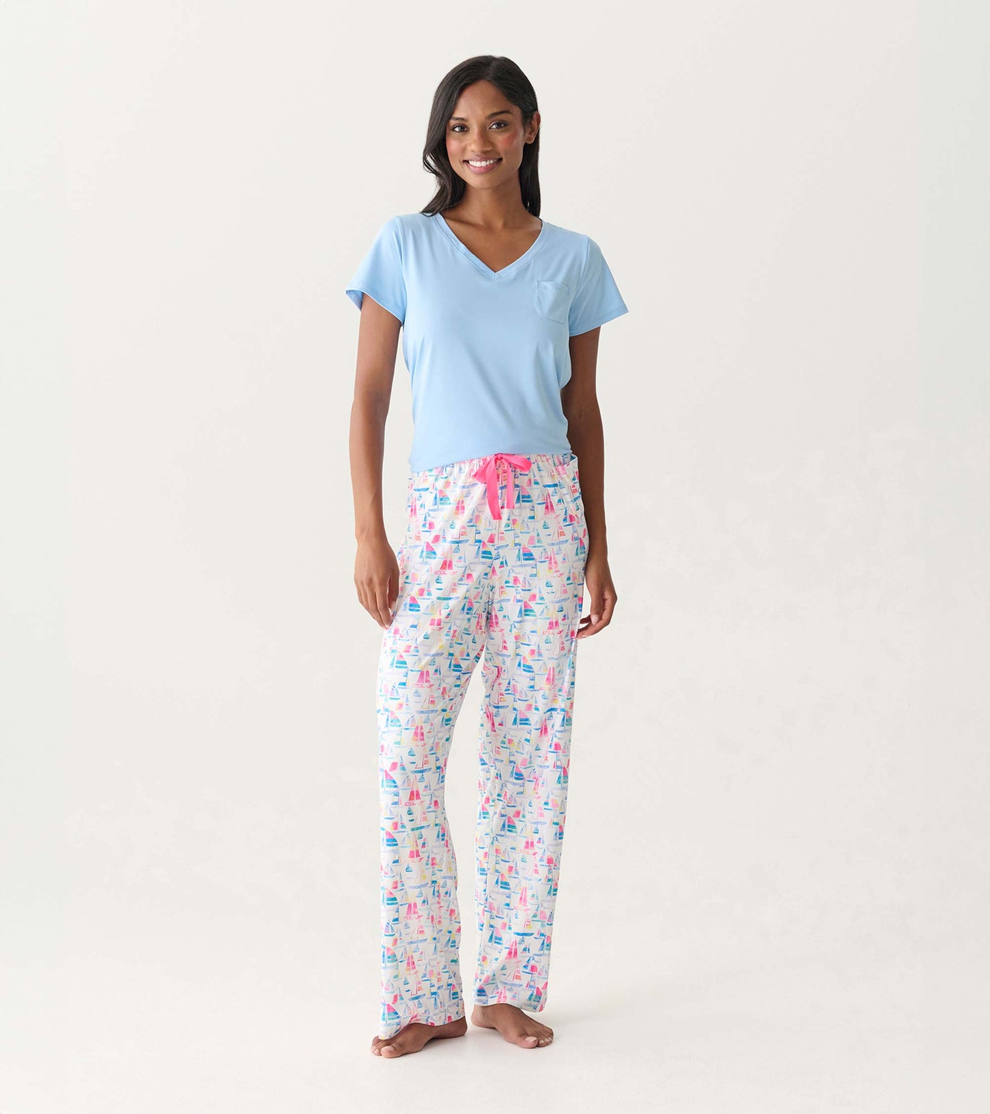 Women's pajama pants with colorful sailboat print, pink drawstring waist, shown on model.