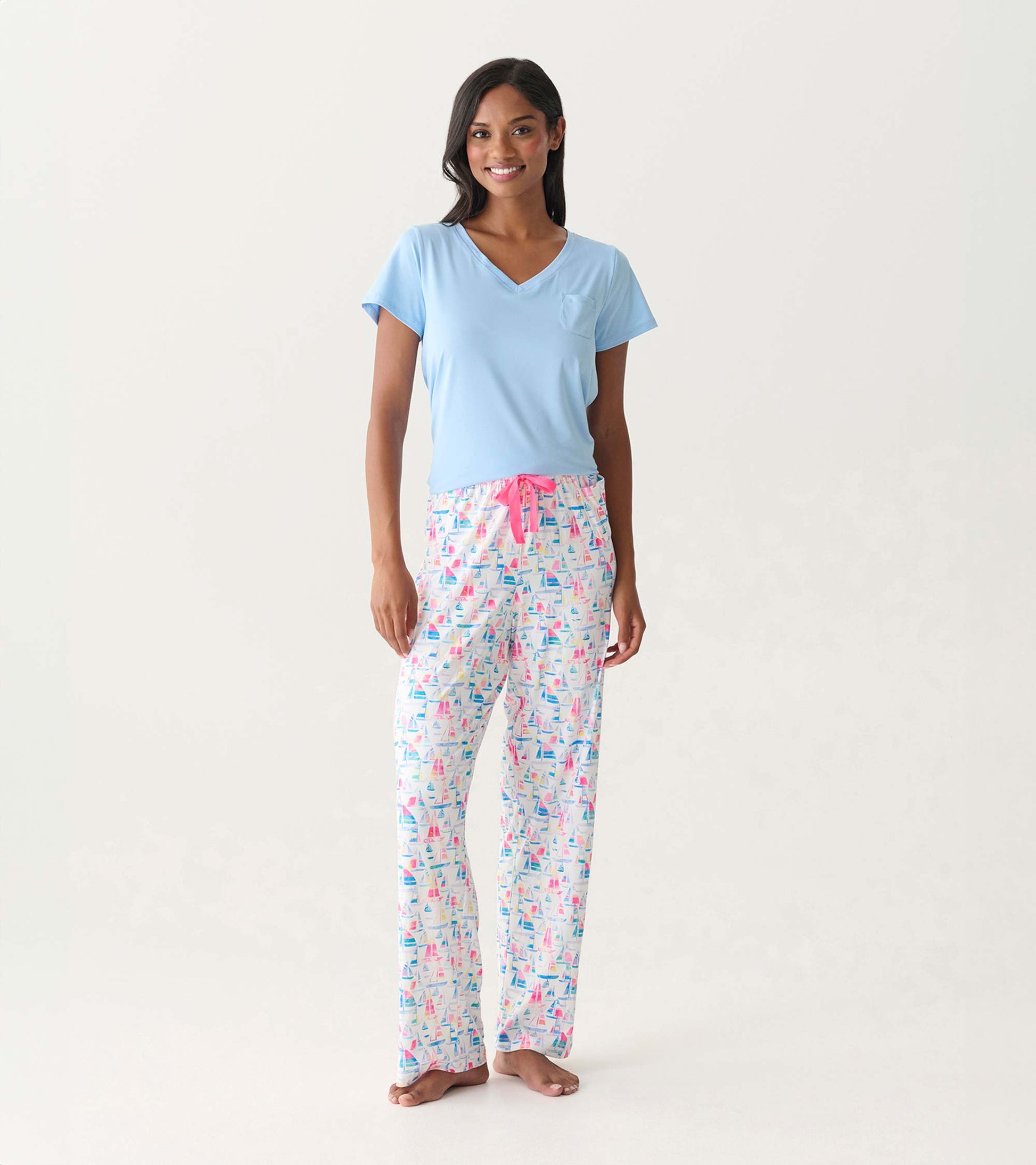 Women's pajama pants with colorful sailboat print, pink drawstring waist, shown on model.