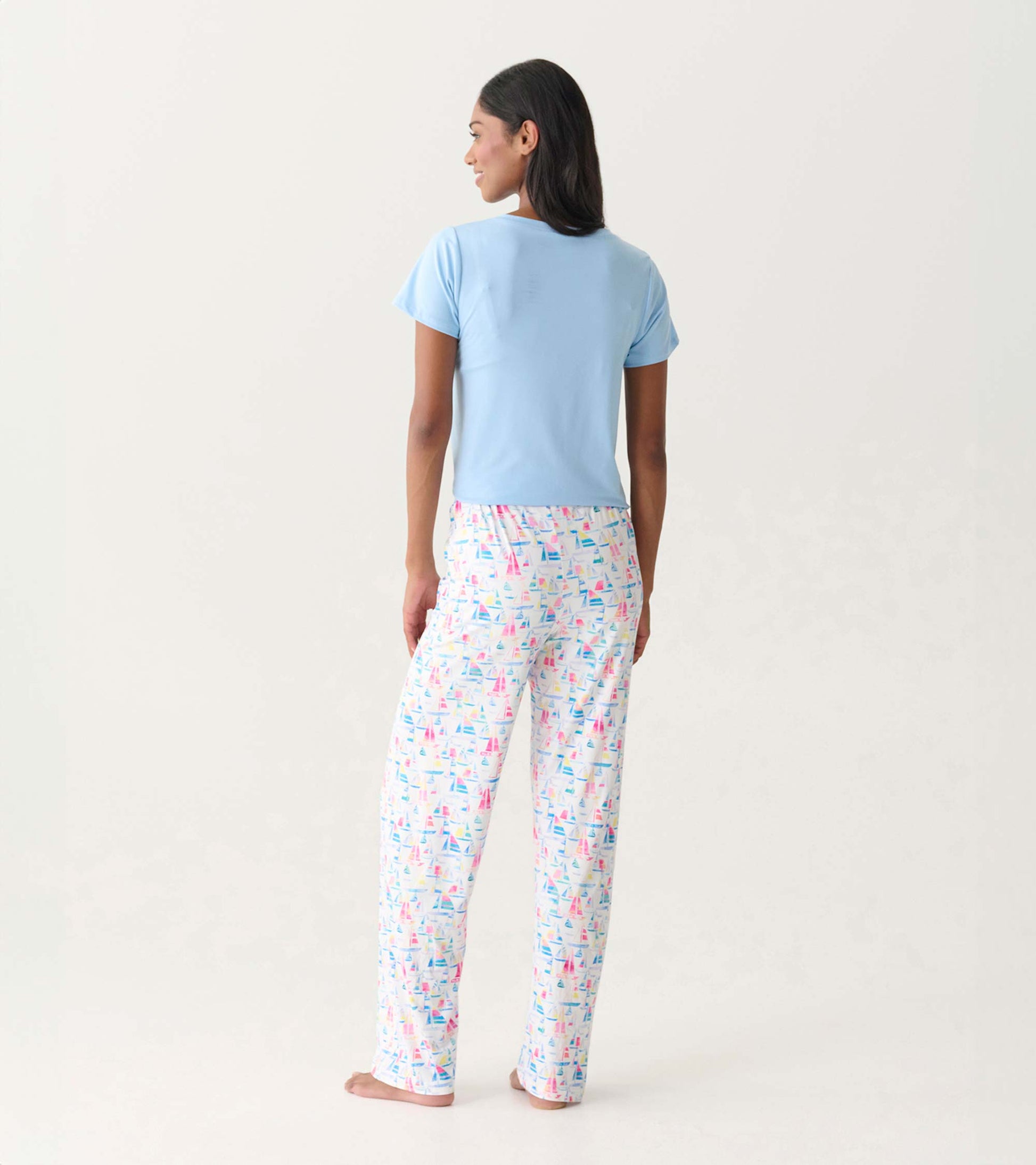 Back view of light blue pajama top with white polyknit pants printed with colorful sailboats