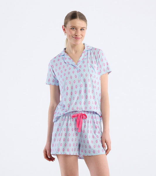 Model wearing blue striped short pajama set with pink floral print, button-front top, and matching shorts