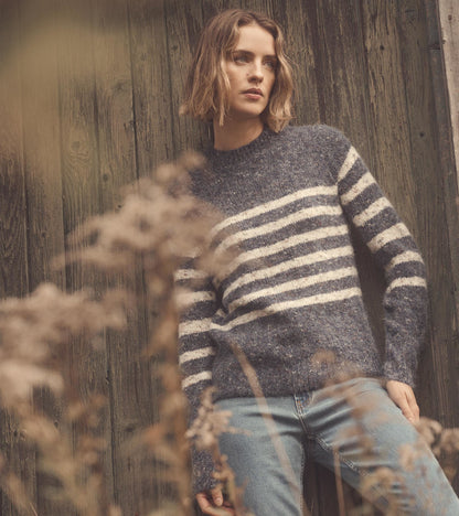 Navy sweater with cream stripes, featuring a relaxed fit and long sleeves, styled with light blue jeans.