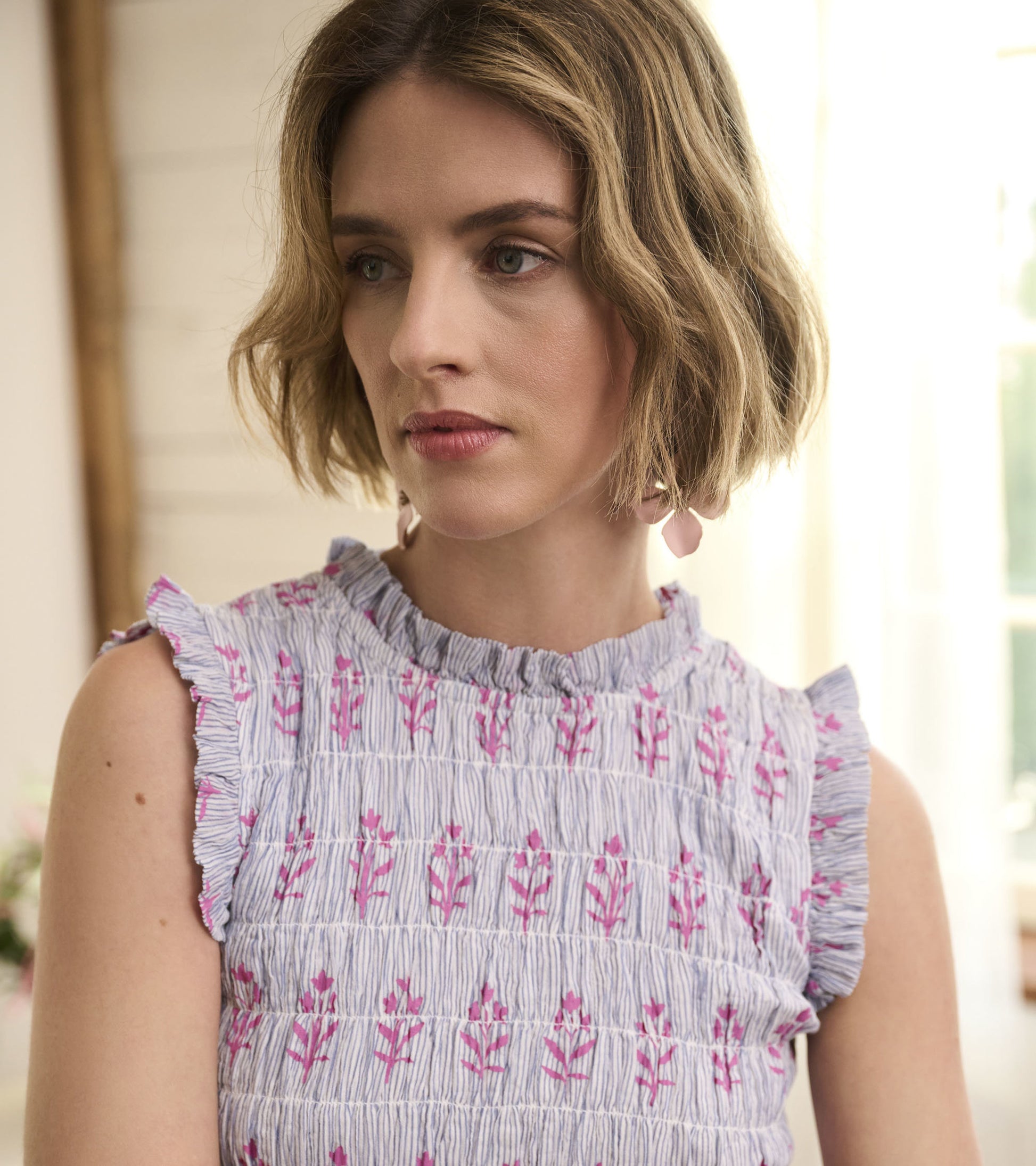 Smocked maxi dress in blue and white seersucker with pink floral pattern and ruffled sleeves.