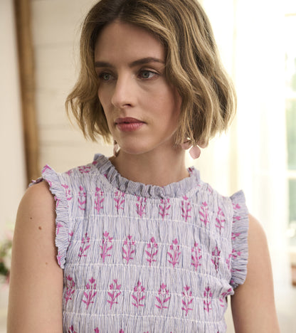 Smocked maxi dress in blue and white seersucker with pink floral pattern and ruffled sleeves.