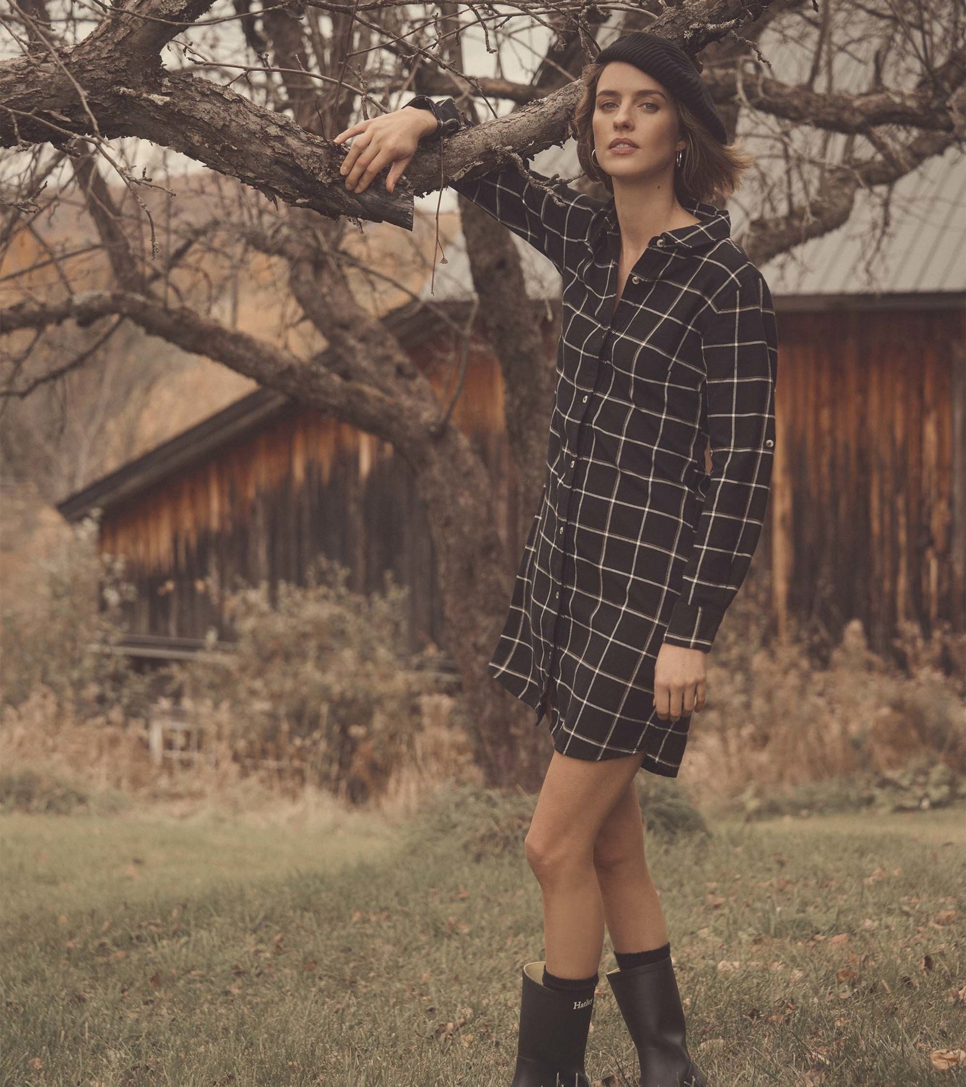 Black windowpane shirt dress with a button-up front, long sleeves, and a relaxed fit, styled with black boots.