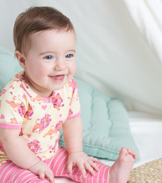 Organic cotton baby pajama set featuring a yellow top with lion prints and pink striped pants, suitable for infants.