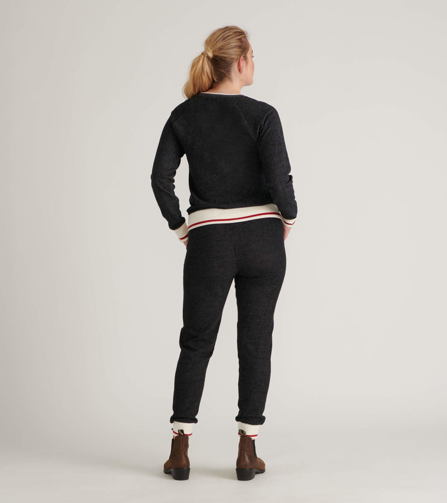 Black pullover with white and red striped cuffs, featuring a relaxed fit and soft fabric, shown from the back.
