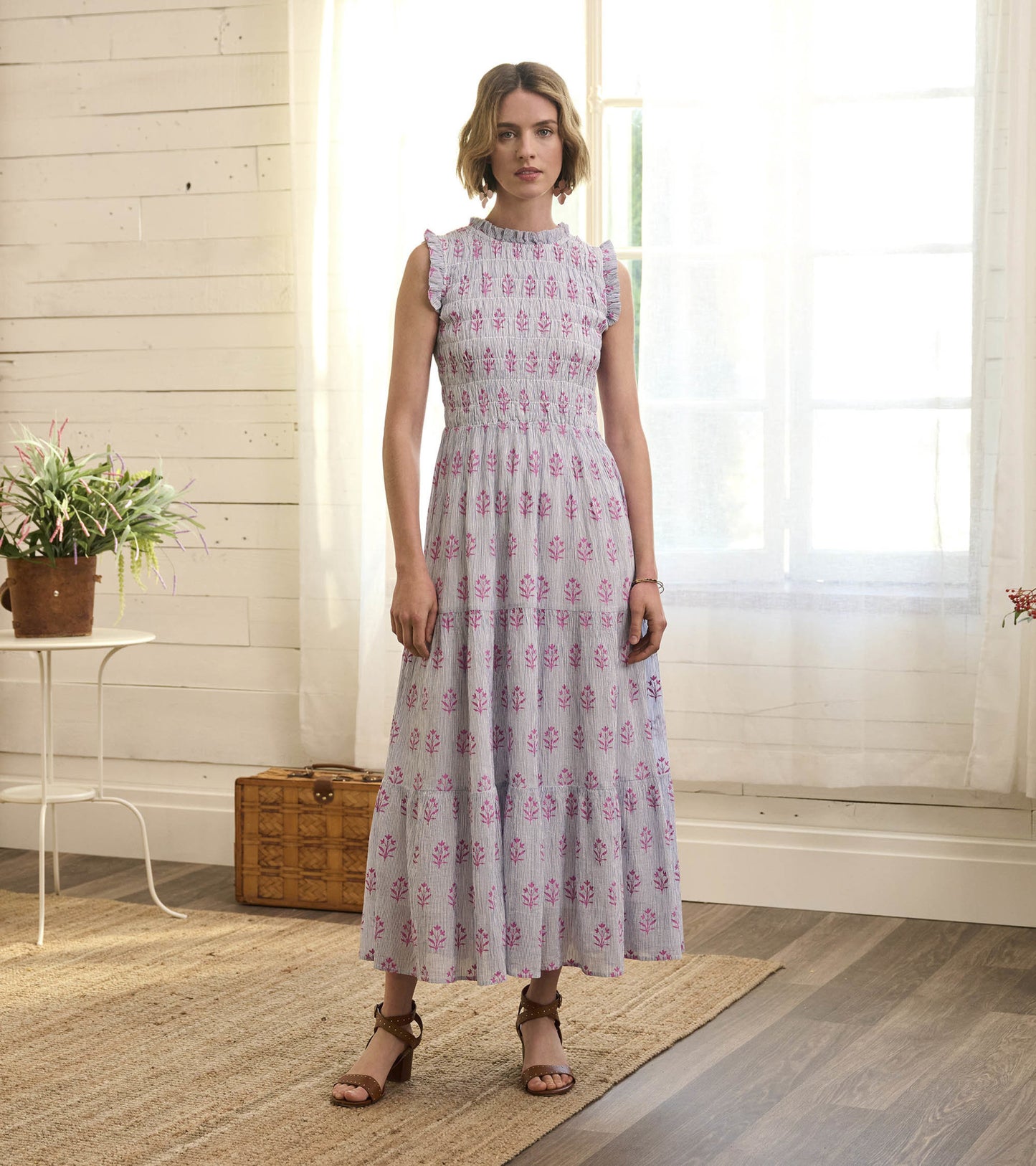 Light gray smocked maxi dress with pink floral pattern, ruffled sleeves, and tiered skirt, styled with brown sandals.