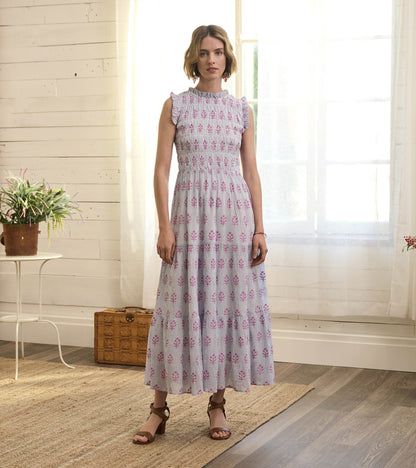 Light gray smocked maxi dress with pink floral pattern, ruffled sleeves, and tiered skirt, styled with brown sandals.