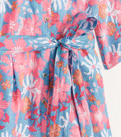 Colorful floral romper featuring pink, blue, and orange patterns, with a tied waist and button details.