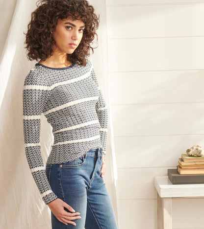 Zigzag patterned sweater in navy and white, featuring long sleeves and a fitted silhouette, paired with blue jeans.