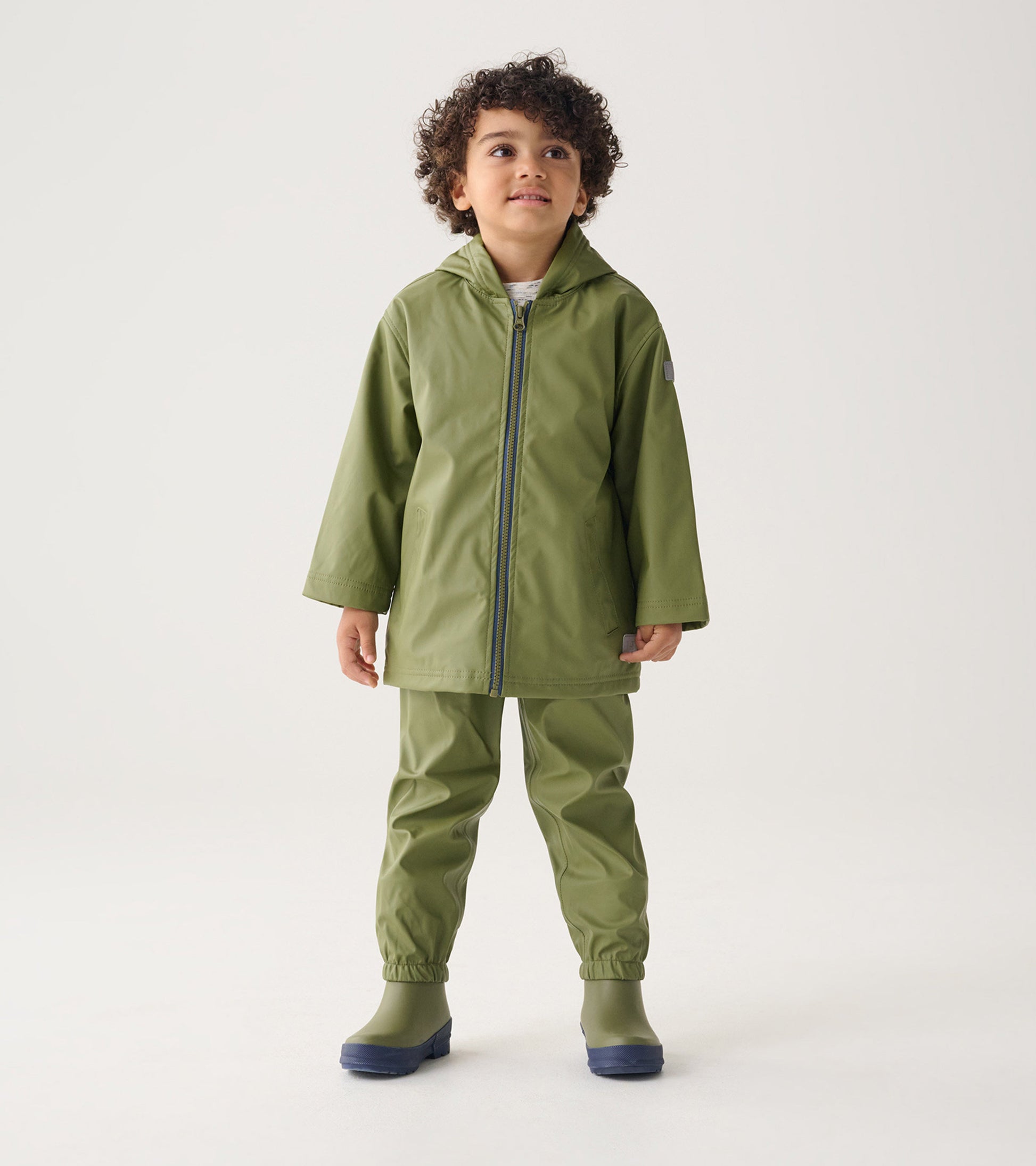 Forest green waterproof rain pants with elastic cuffs, paired with a matching jacket and boots, suitable for kids.