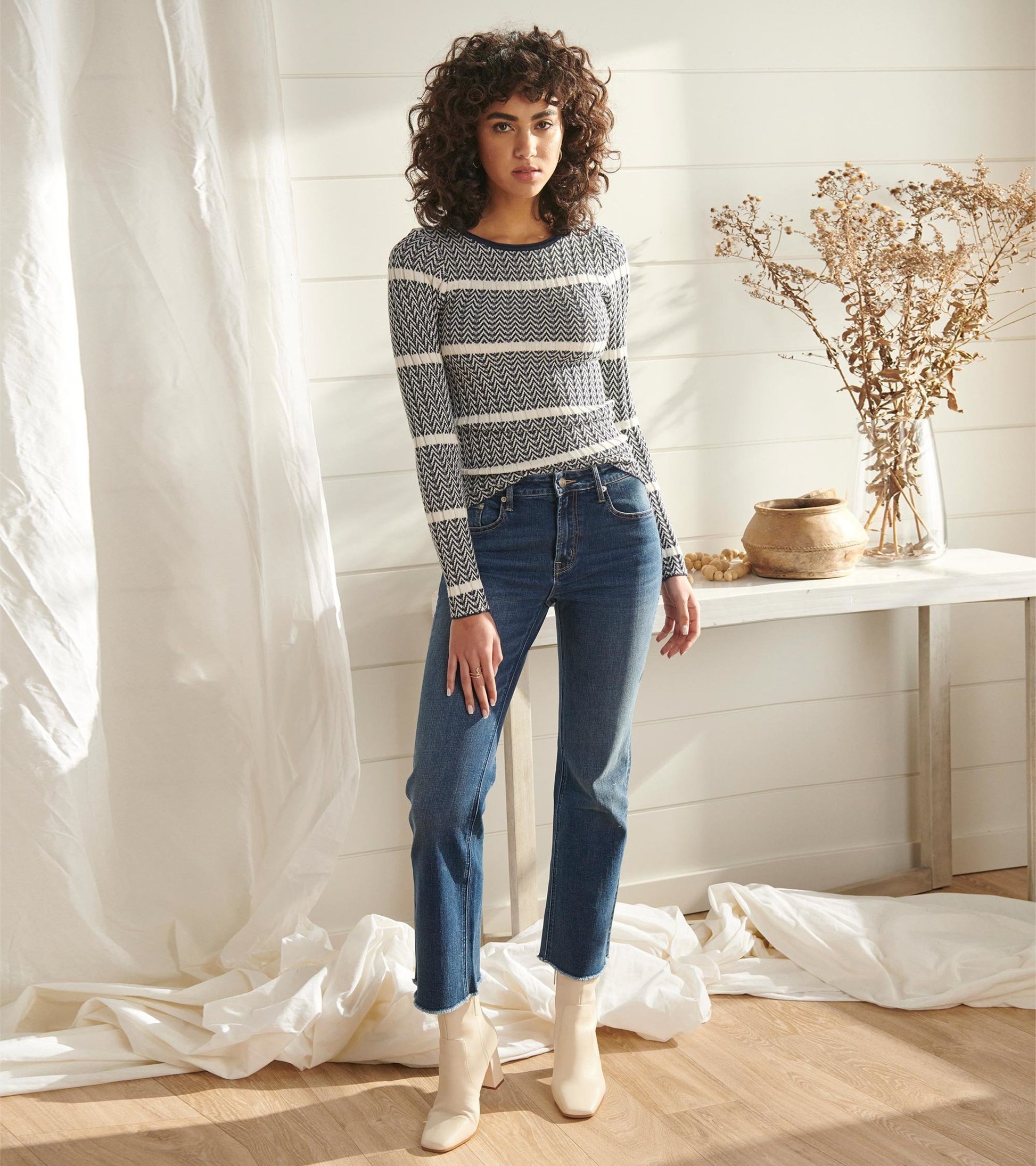 Long-sleeve zigzag patterned sweater in navy and white, paired with high-waisted jeans and ankle boots.
