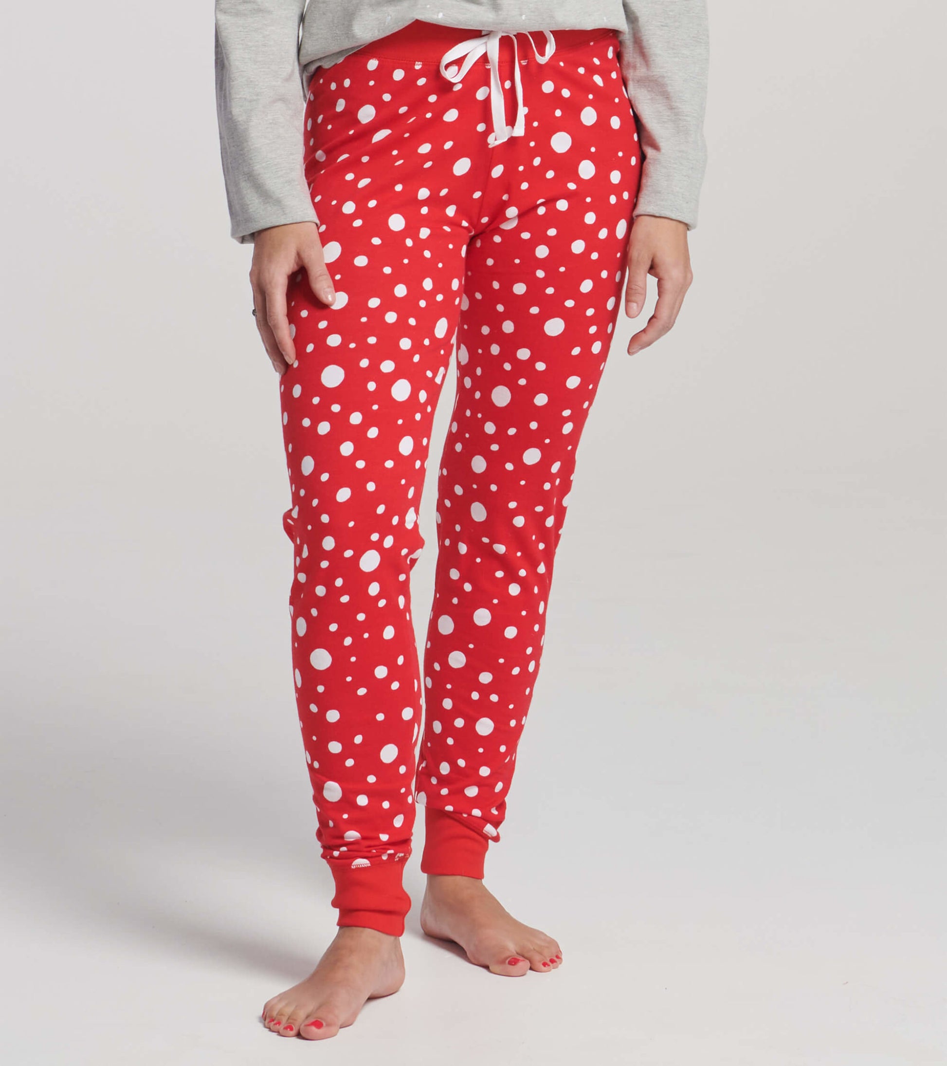 Red leggings with white polka dots, featuring a drawstring waist and fitted cuffs, ideal for Christmas sleepwear.