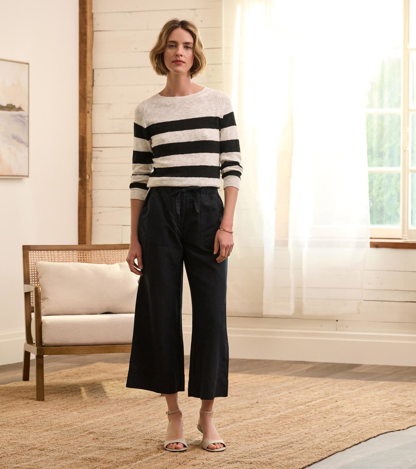 Caviar linen tie front pants in a wide-leg style, paired with a striped sweater and sandals, set in a bright room.