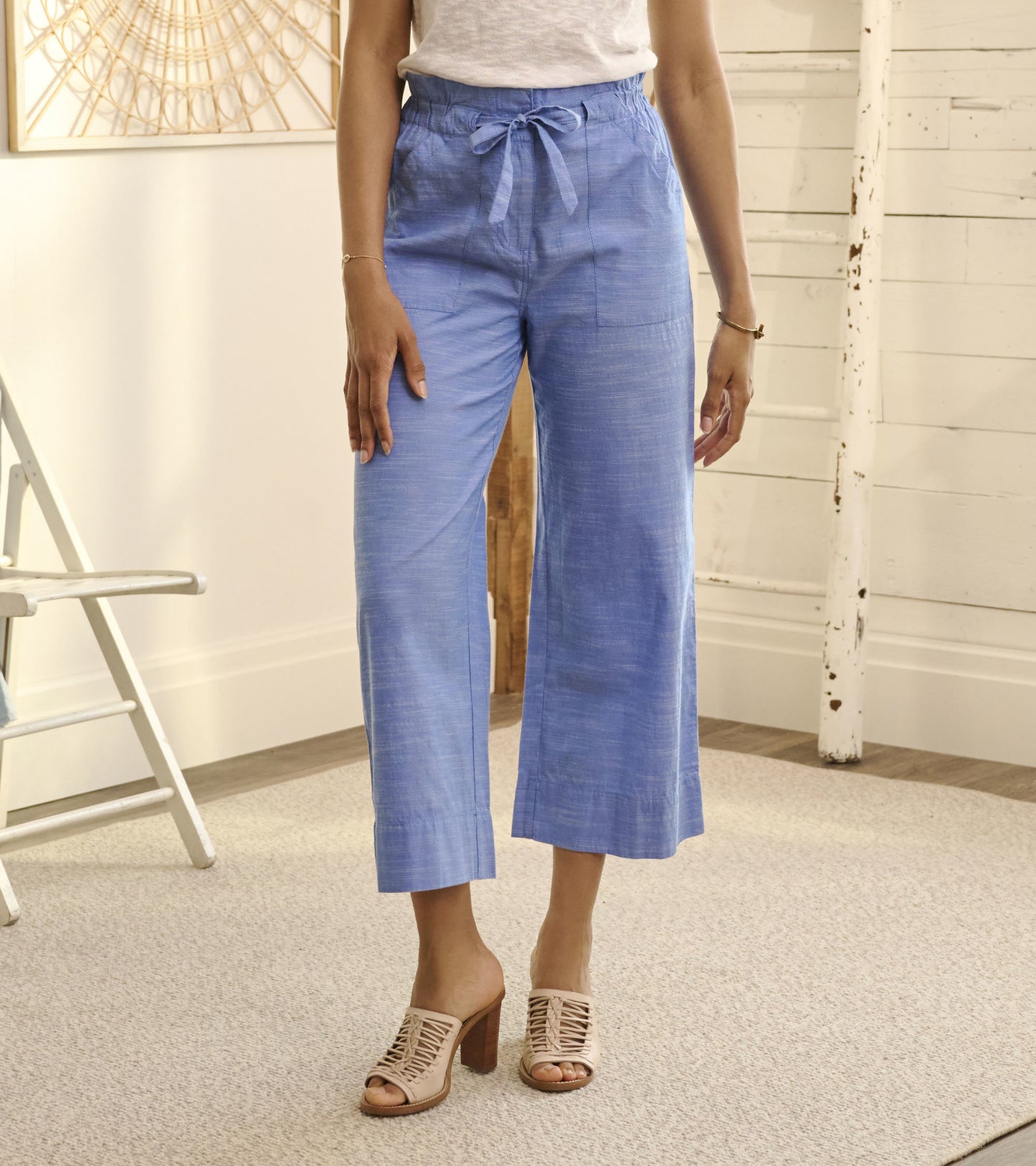 Light blue chambray tie front pants with a relaxed fit and wide legs, styled with a casual top and heeled sandals.