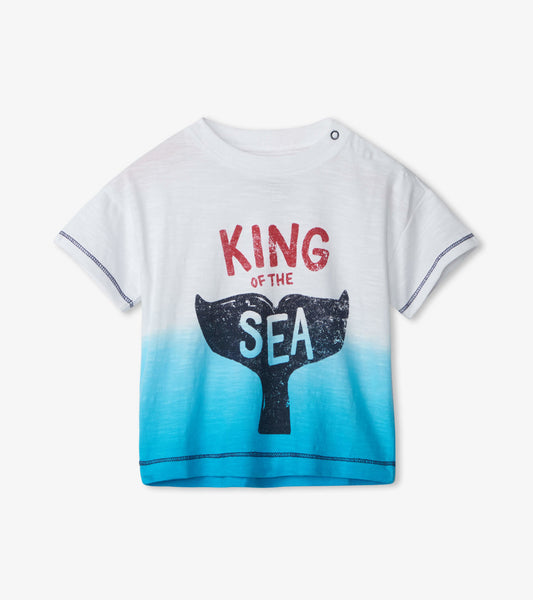 White baby tee with blue ombre, featuring a whale tail graphic and "KING OF THE SEA" text in red and blue.