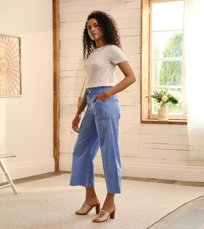 Light blue chambray tie front pants with a relaxed fit and side pockets, styled with a white top and heeled sandals.