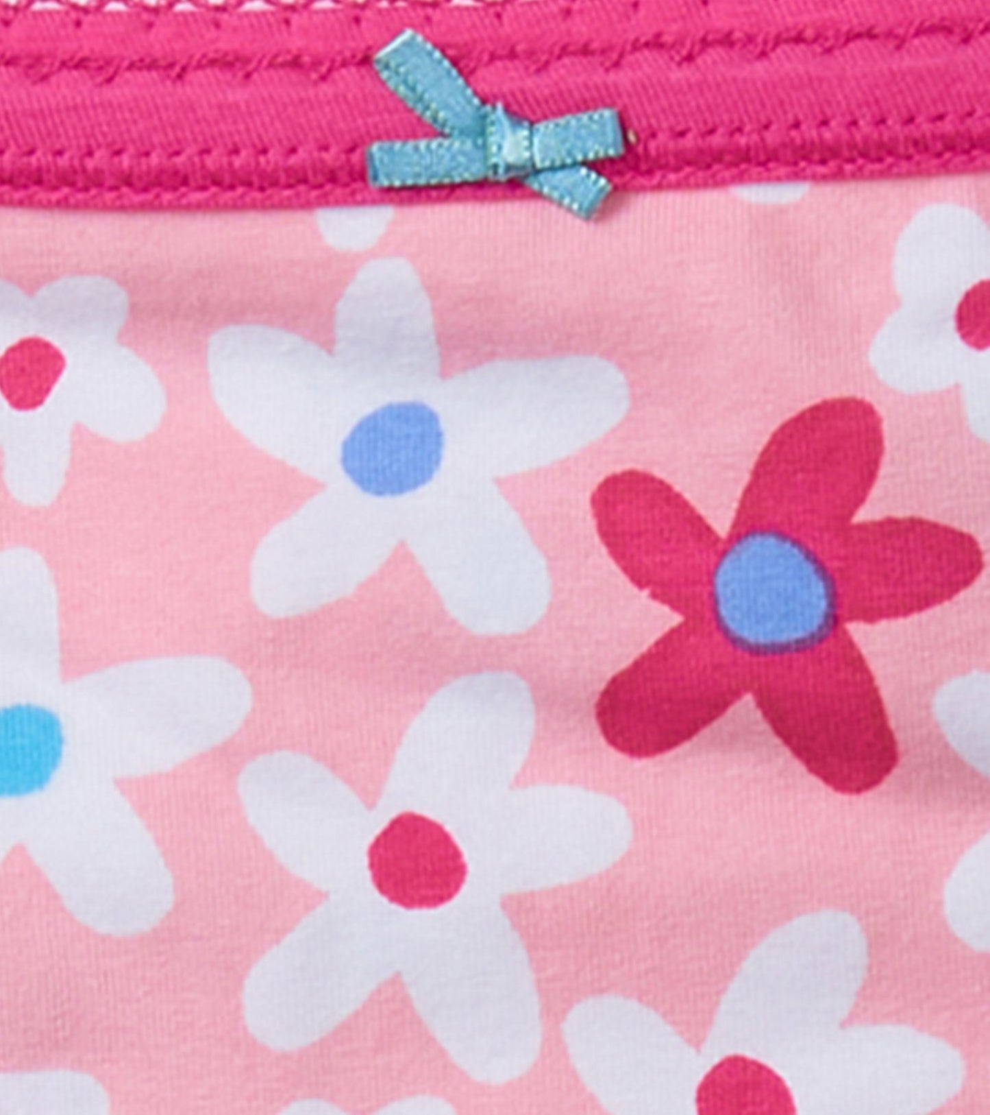 Pink cotton brief with a floral pattern, featuring white and red flowers, and a small blue bow on the waistband.