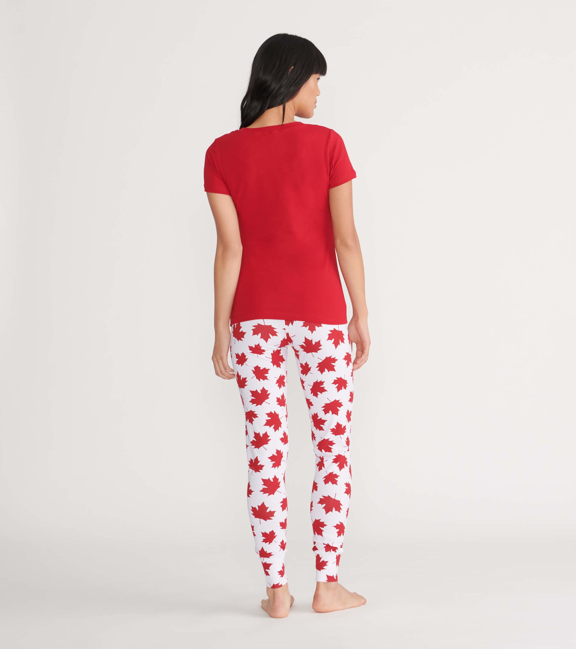 Red short-sleeve women's tee paired with white leggings featuring red maple leaf patterns, viewed from the back.