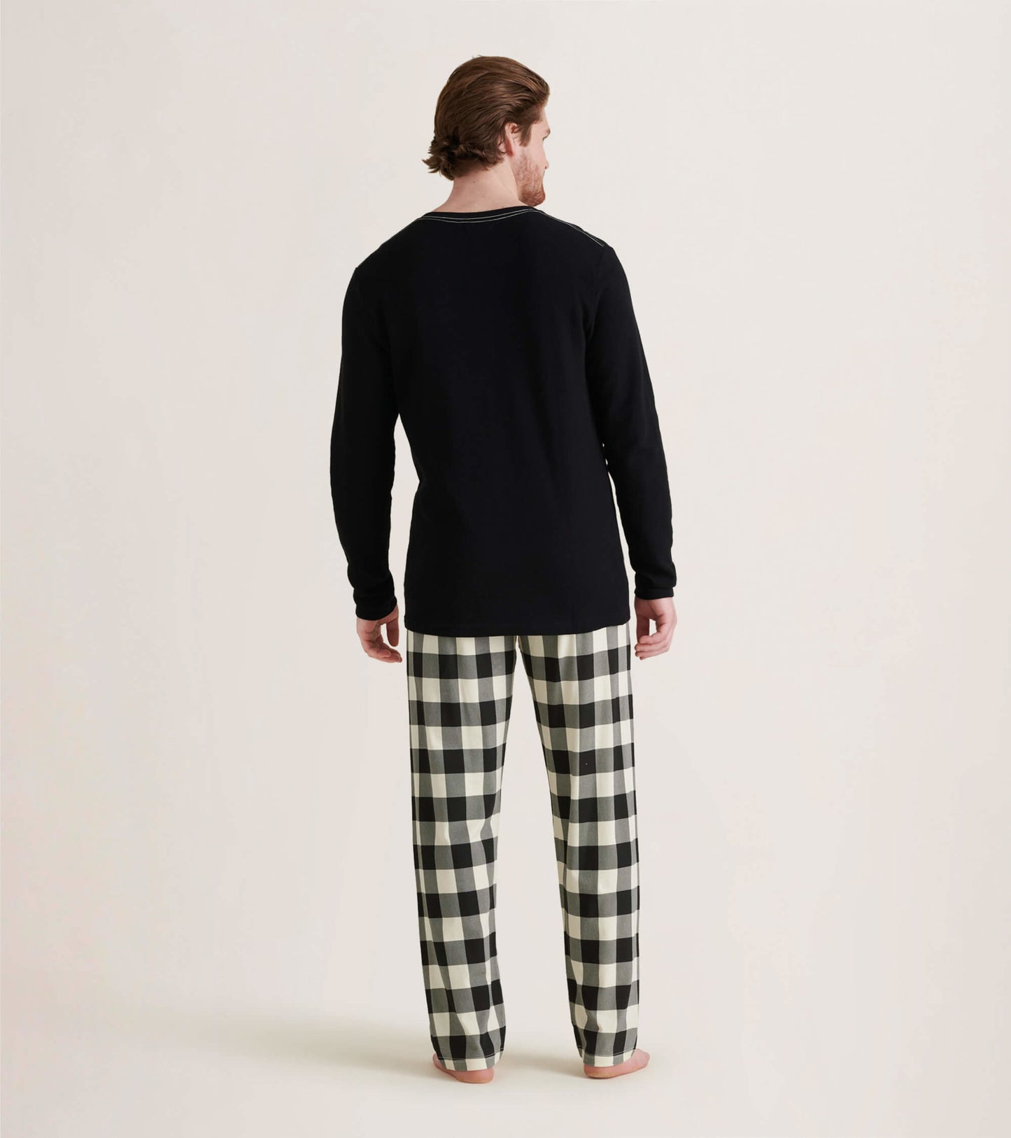 Men's black waffle henley shirt paired with black and white checkered pajama pants, viewed from the back.