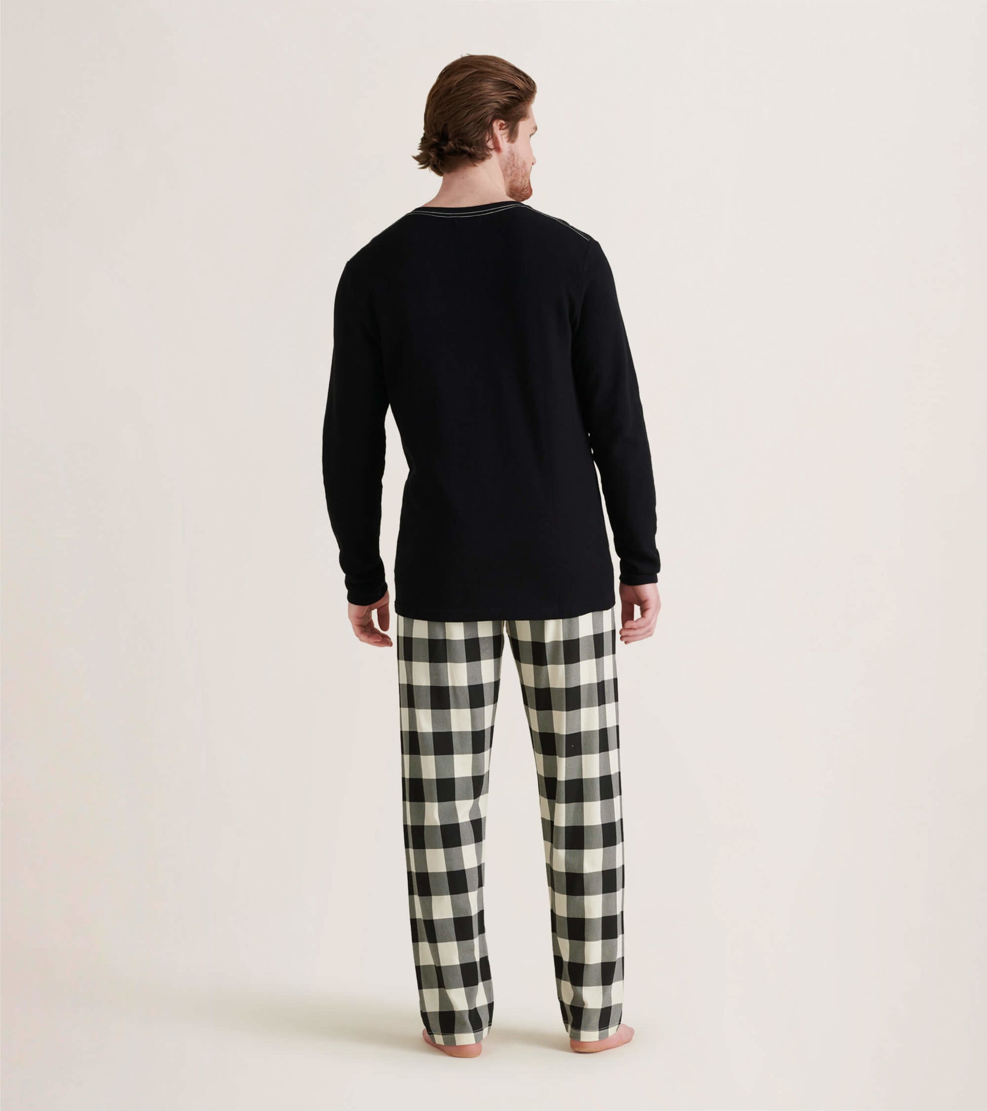 Men's black waffle henley shirt paired with black and white checkered pajama pants, viewed from the back.