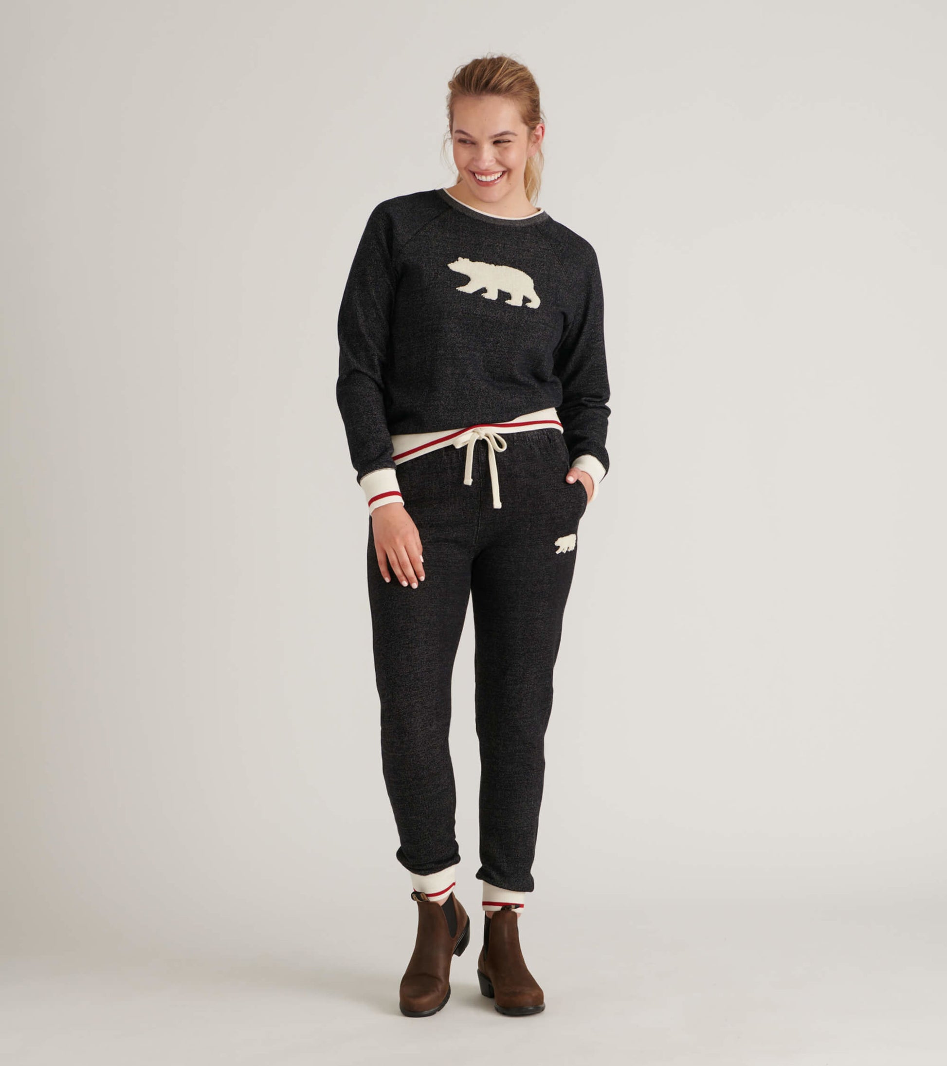 Black pullover with a cream bear graphic, featuring ribbed cuffs and a drawstring waist, styled with matching pants.