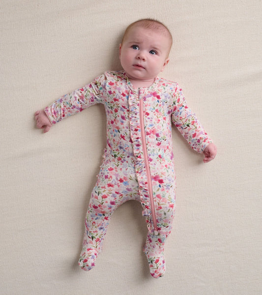 Floral-patterned footed sleeper with ruffles, featuring a front zipper and long sleeves, suitable for infants.