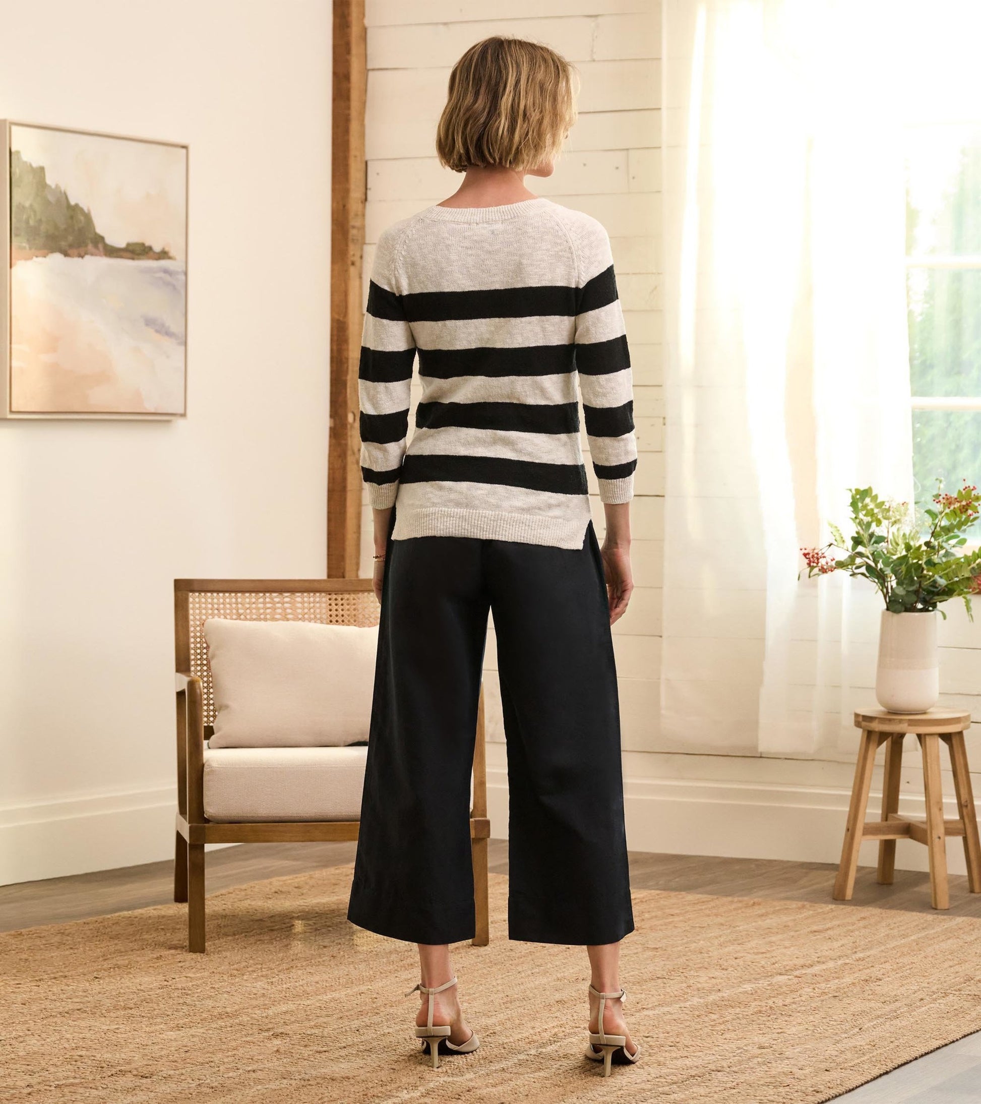Black linen tie front pants with wide legs, styled with a striped sweater, viewed from the back in a cozy interior setting.