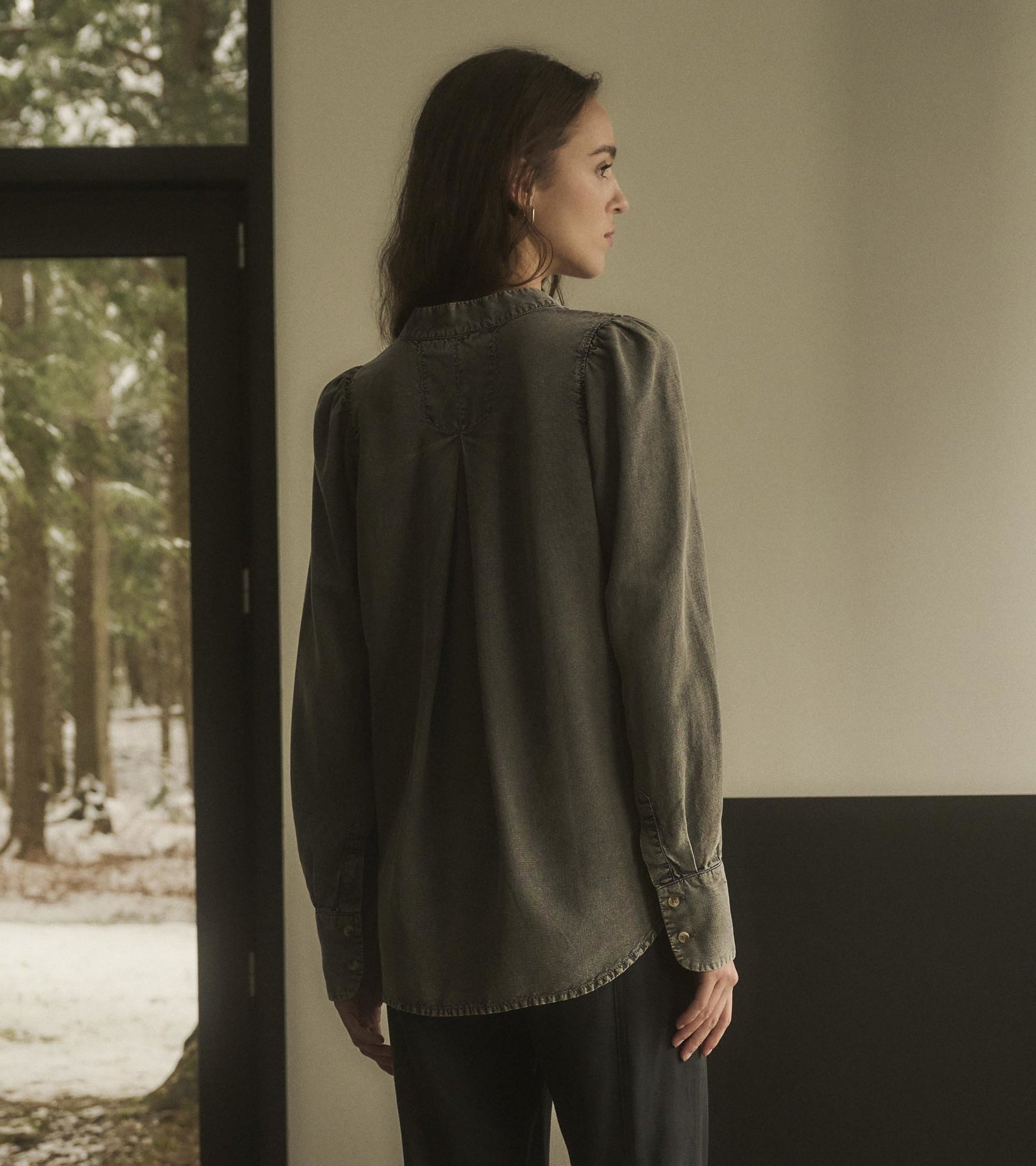 Black acid wash blouse with long sleeves and buttoned cuffs, featuring a relaxed fit and back pleat detail.