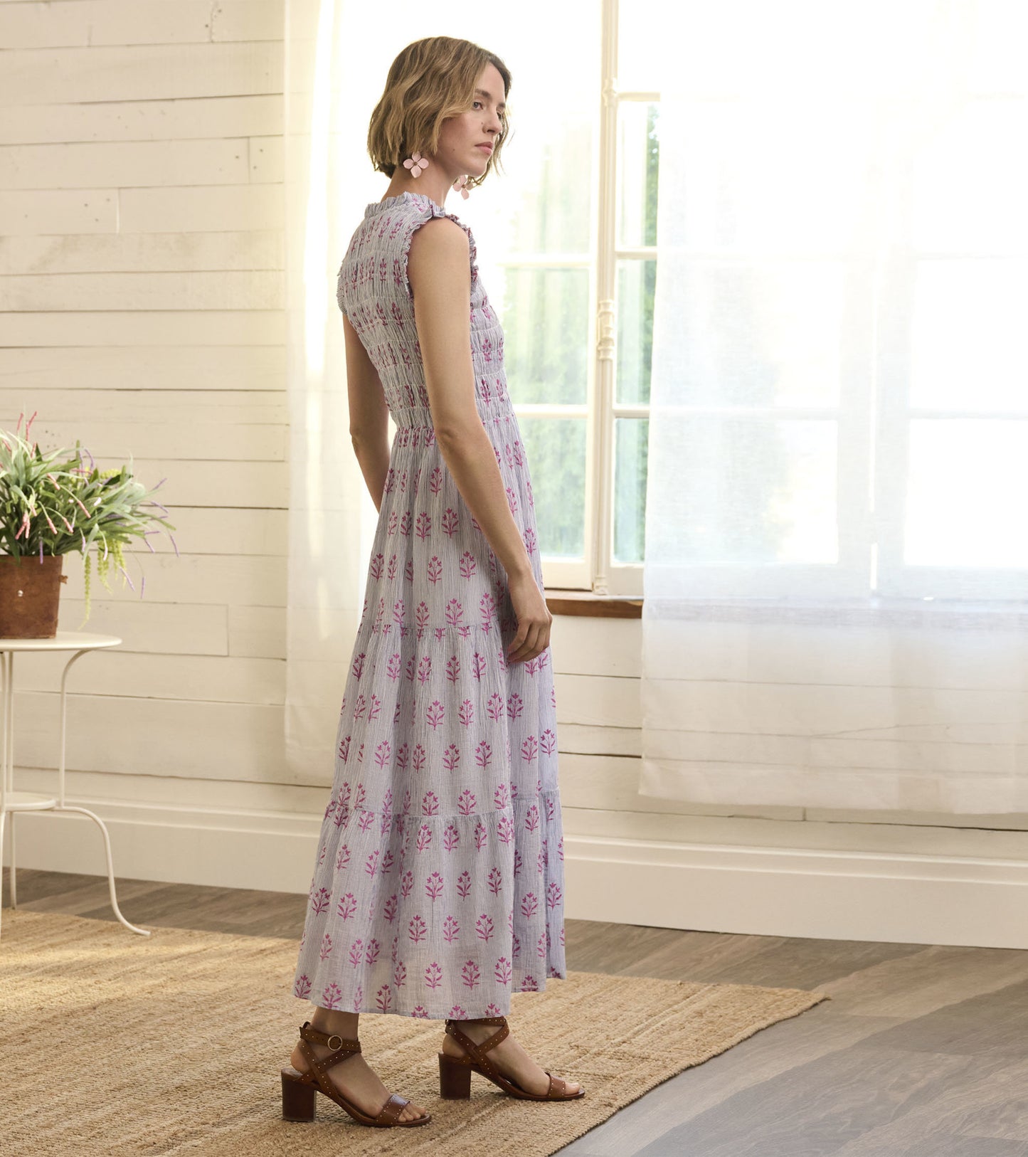Light purple smocked maxi dress with floral print, featuring a tiered skirt and cap sleeves, styled with brown sandals.