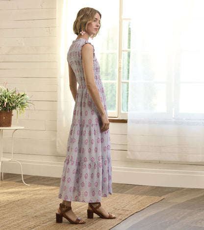 Light purple smocked maxi dress with floral print, featuring a tiered skirt and cap sleeves, styled with brown sandals.