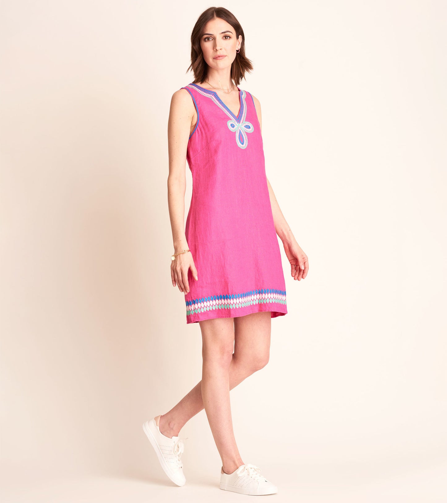 Fuchsia sleeveless sheath dress with a V-neck and decorative blue trim at the hem, styled with white sneakers.