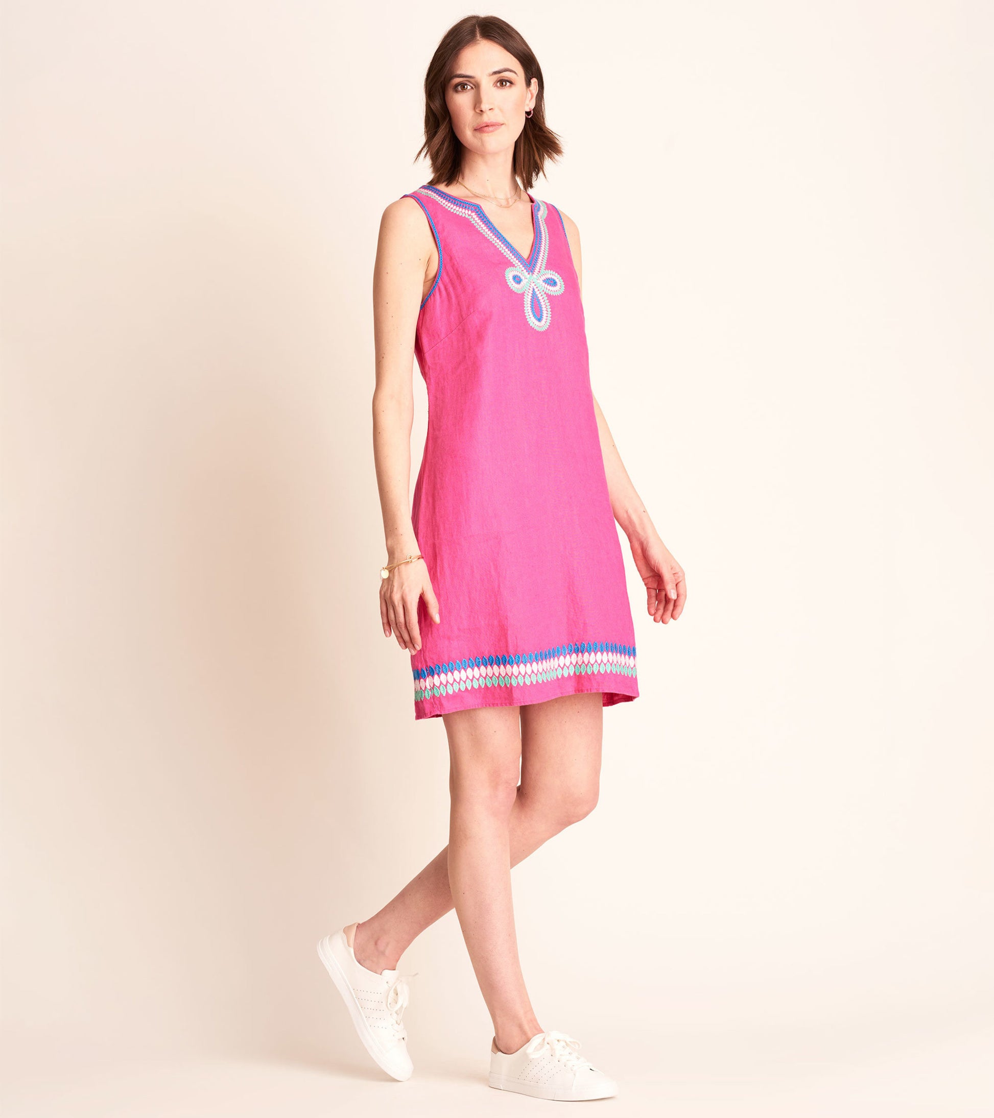 Fuchsia sleeveless sheath dress with a V-neck and decorative blue trim at the hem, styled with white sneakers.