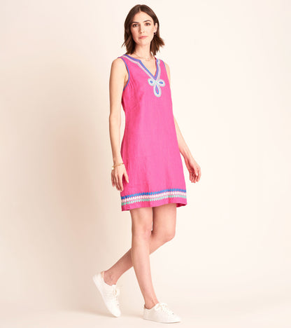 Fuchsia sleeveless sheath dress with a V-neck and decorative blue trim at the hem, styled with white sneakers.