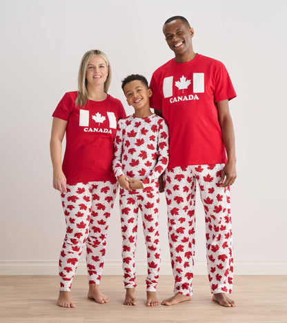 Red pajama set featuring white maple leaf patterns, suitable for kids and adults, worn by a family of three.