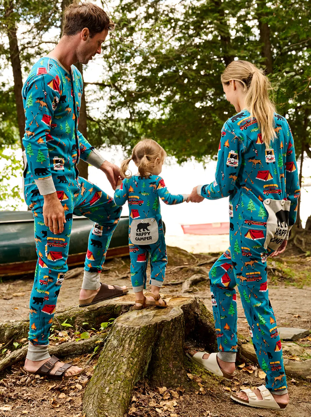 Shop women's onesies. Showing family outdoors wearing matching blue camping-print onesies.