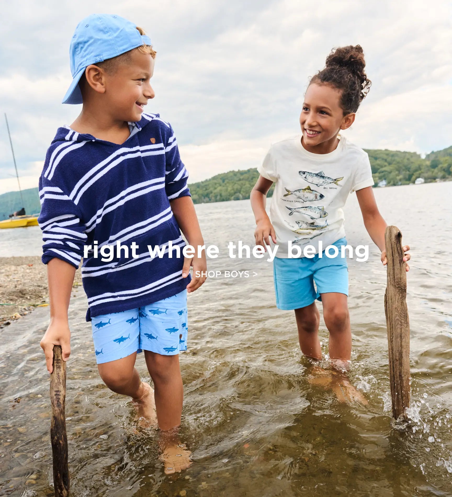 Promotes boys' clothing collection. Showing two kids wading in a lakeshore wearing casual summer outfits.