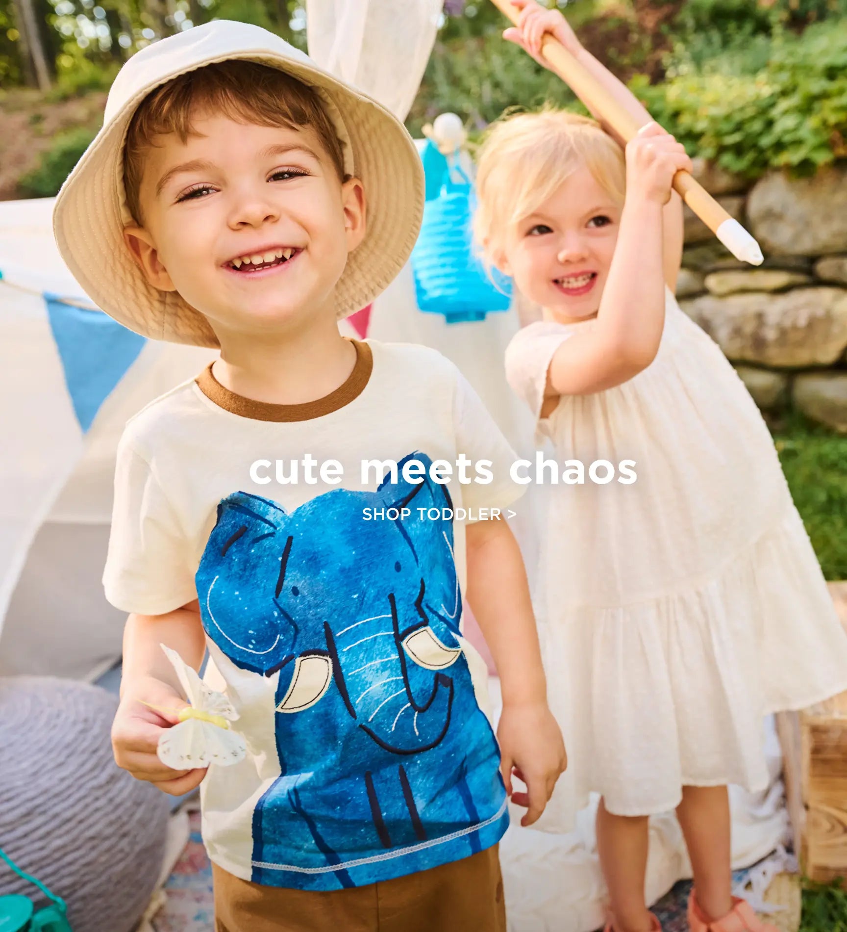 Shop toddler clothing. Showing smiling toddlers playing outdoors, one in an elephant graphic tee.